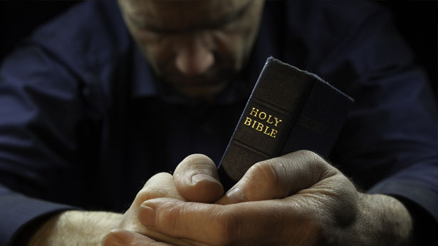 Man-praying-with-Bible-via-Shutterstock